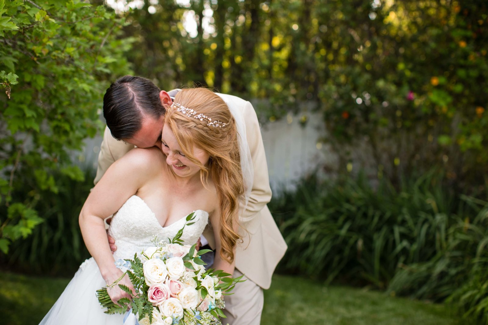 Groom kisses the bride as she laughs at Heritage House in Arroyo Grande