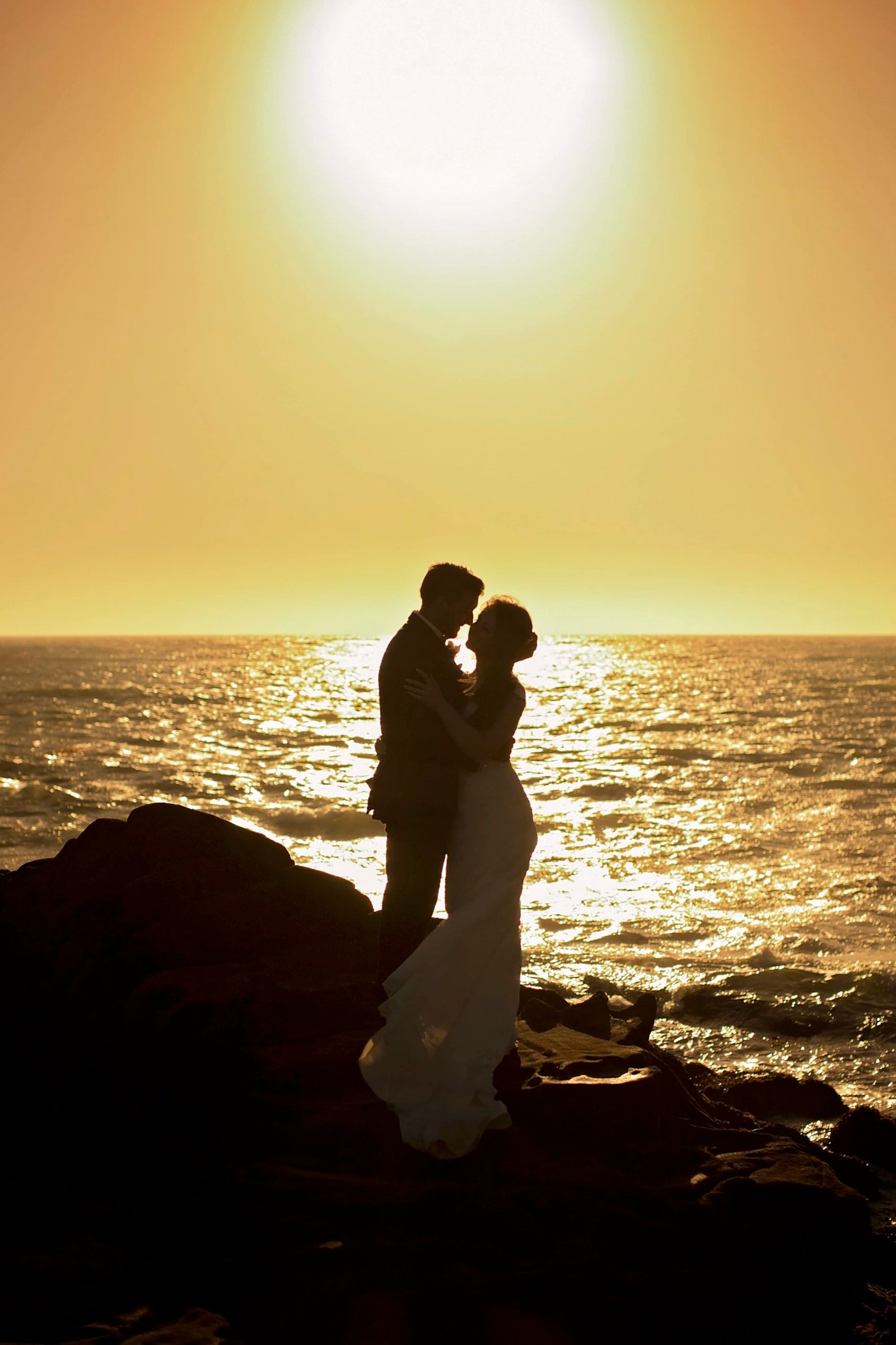 Bride and groom kiss at sunset on the beach