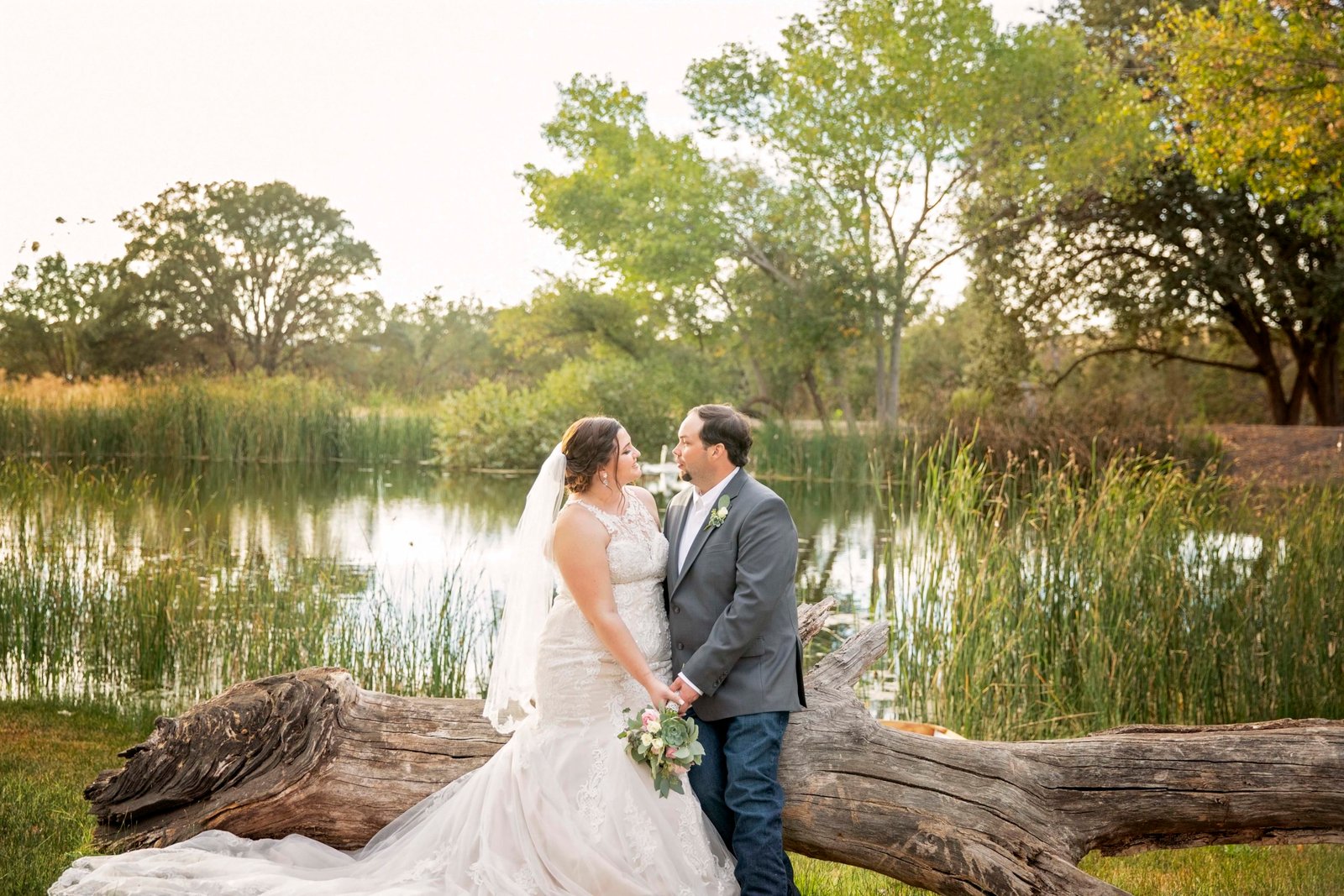 Bride and groom pose in front of the pond at Fallen Oaks Estate