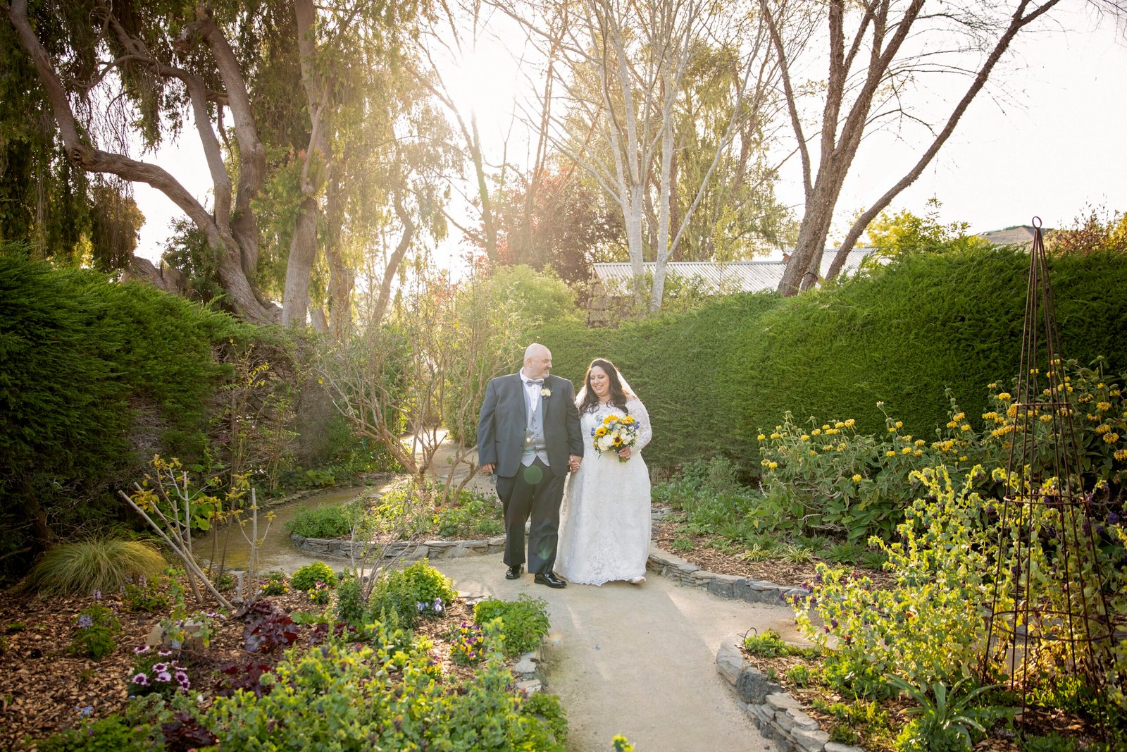 couple walking along a path in a garden after their wedding