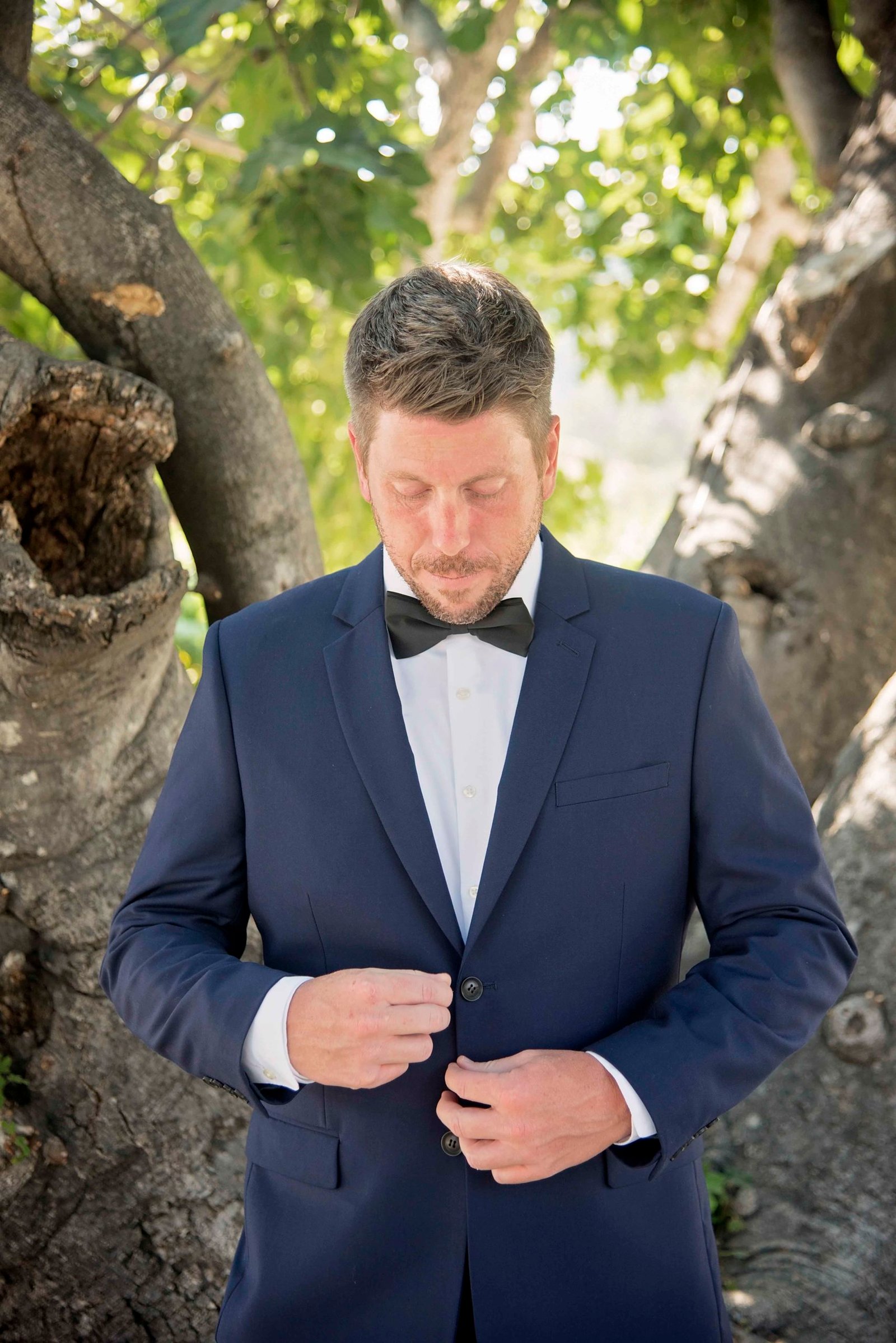 groom buttoning his jacket at Higuera Ranch