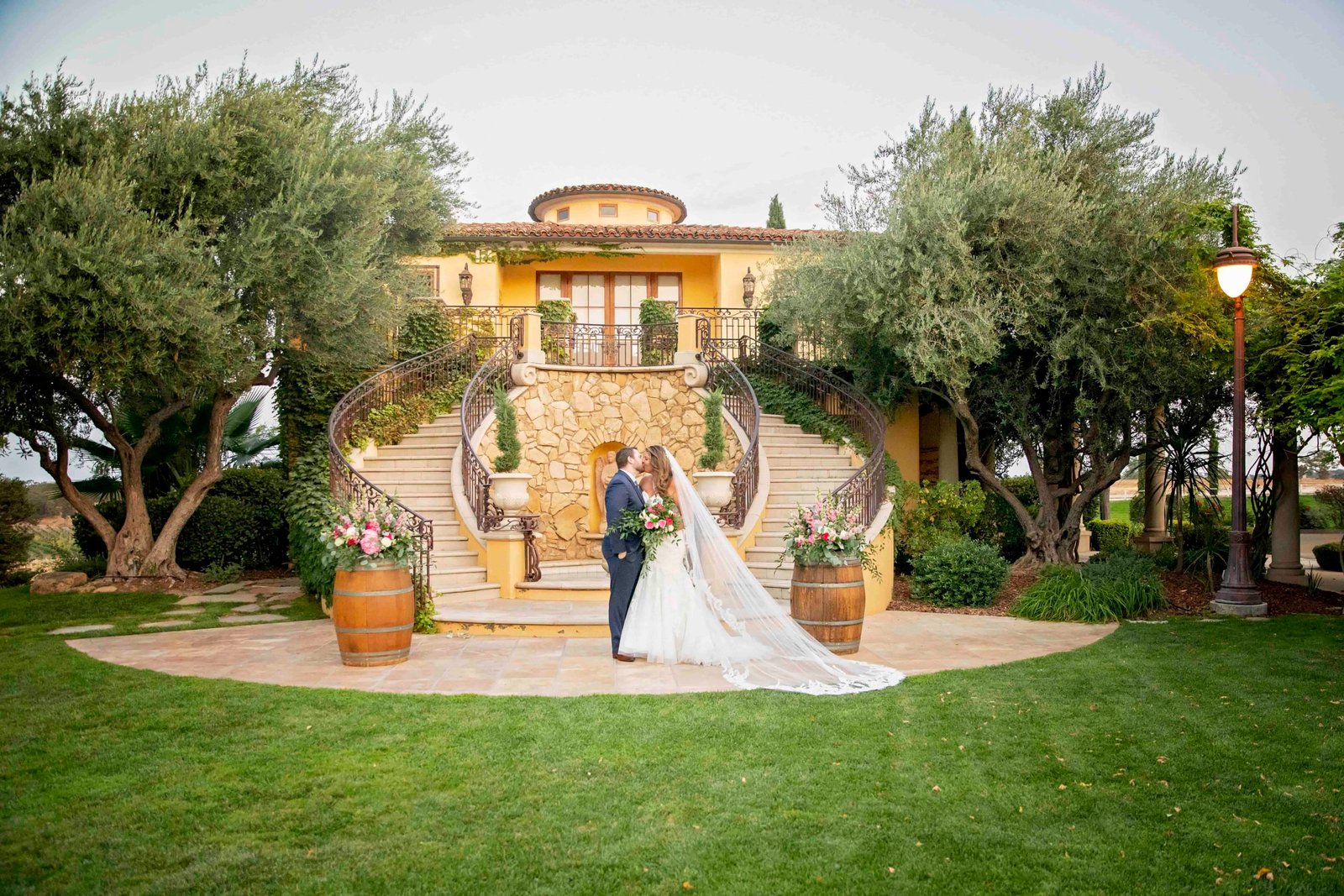 Bride and groom kissing in front of the grand staircase at CaliPaso Winery