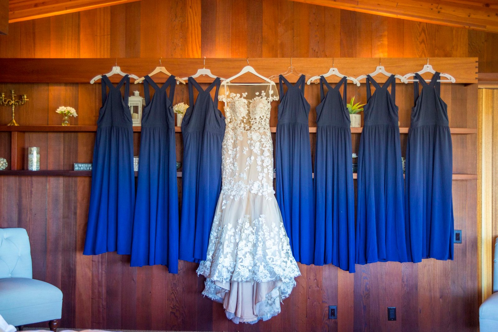 wedding dress and royal blue bridesmaid dresses hanging on a wall at Opolo