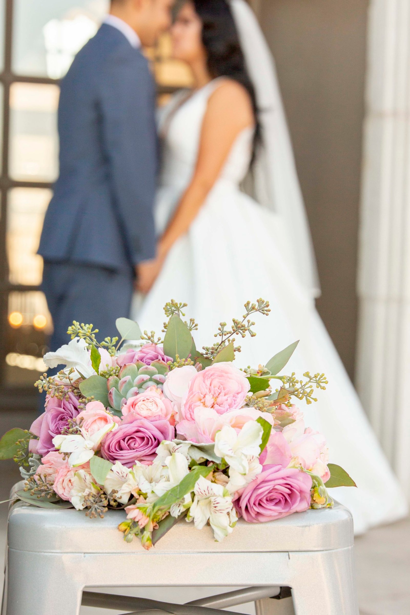 bridal bouquet with bride and groom in the background