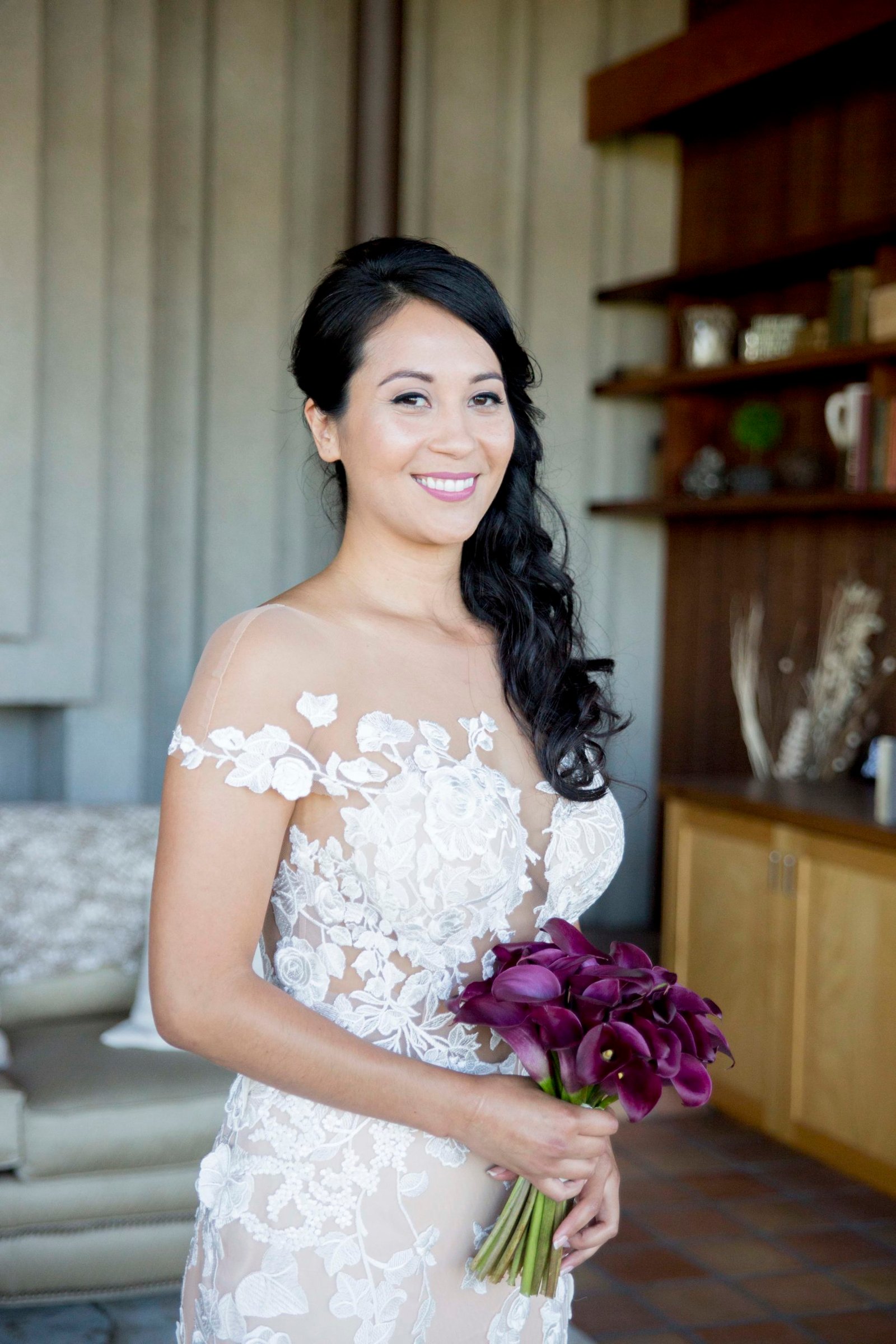 bride smiling while holding a burgundy bouquet