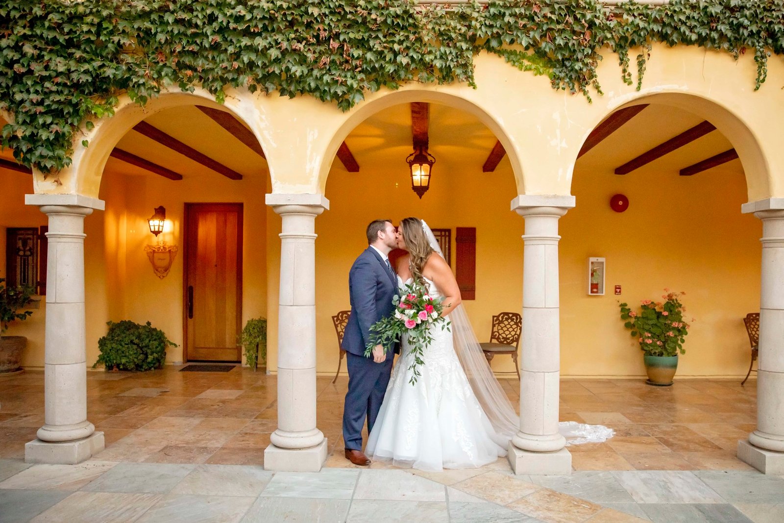 Bride and groom kissing under an archway