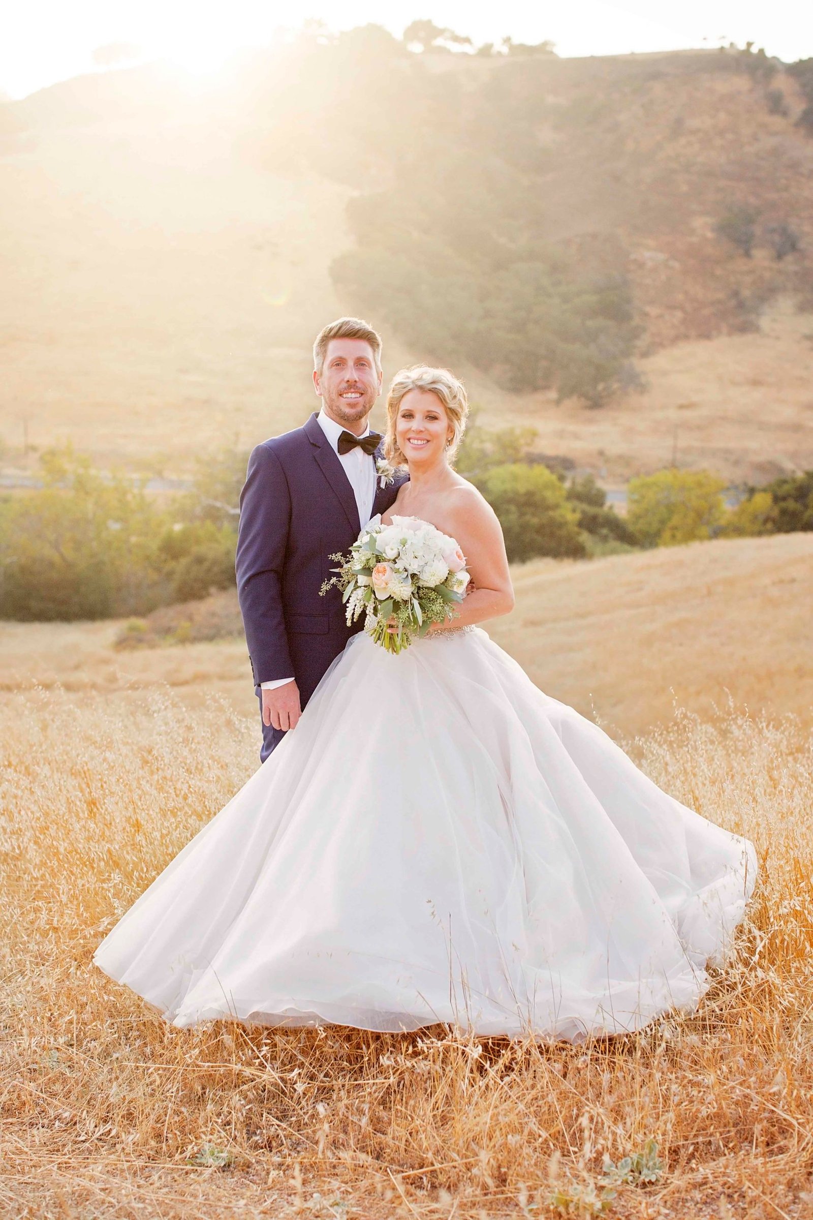 Bride and groom pose in an open field at Higuera Ranch