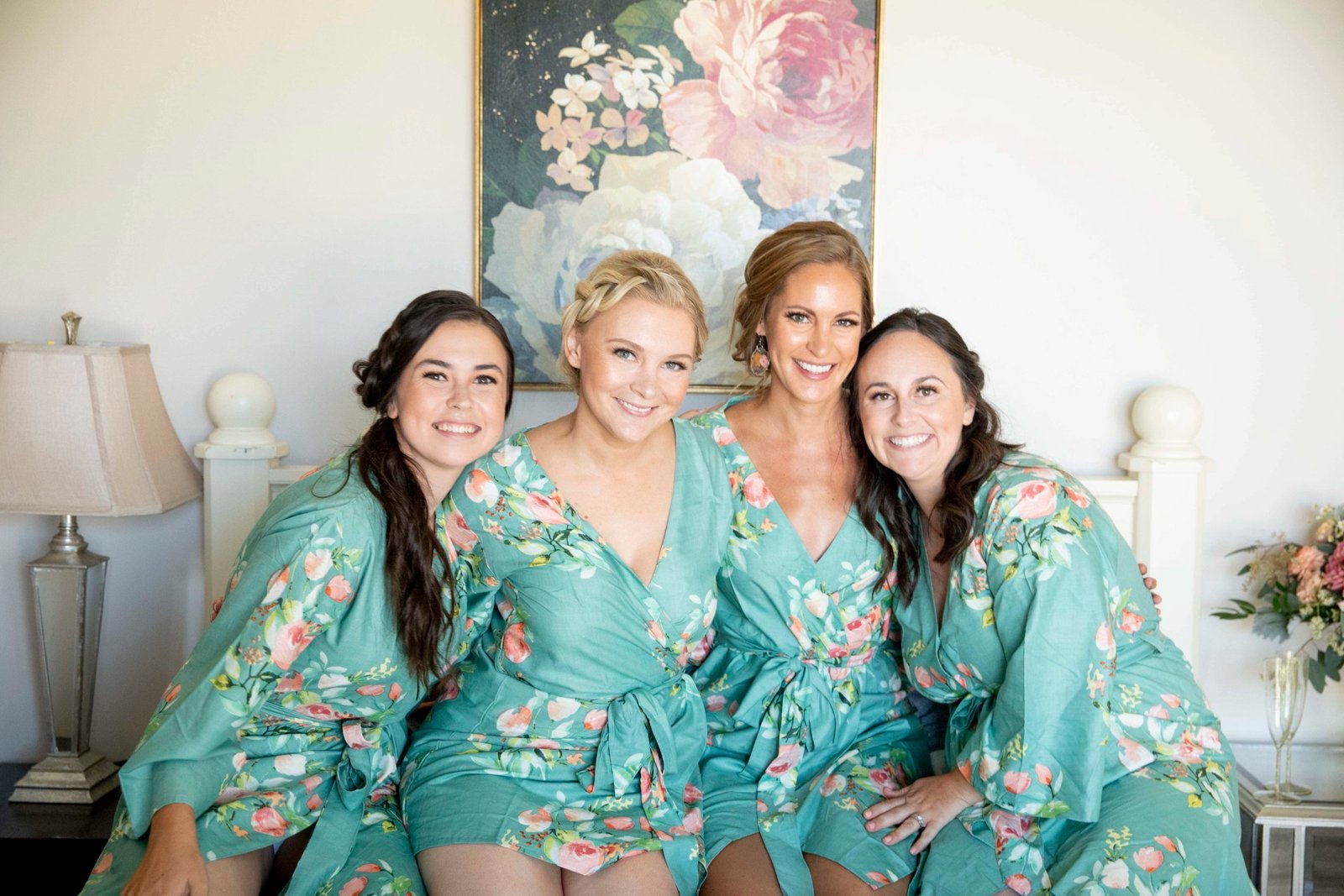 bride with bridesmaids in matching robes on a bed