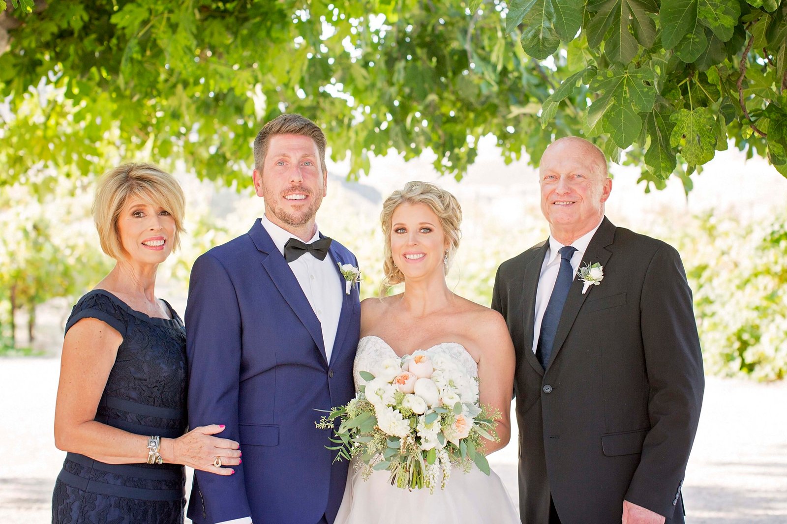 Bride and groom pose with the bride's parents at Higuera Ranch