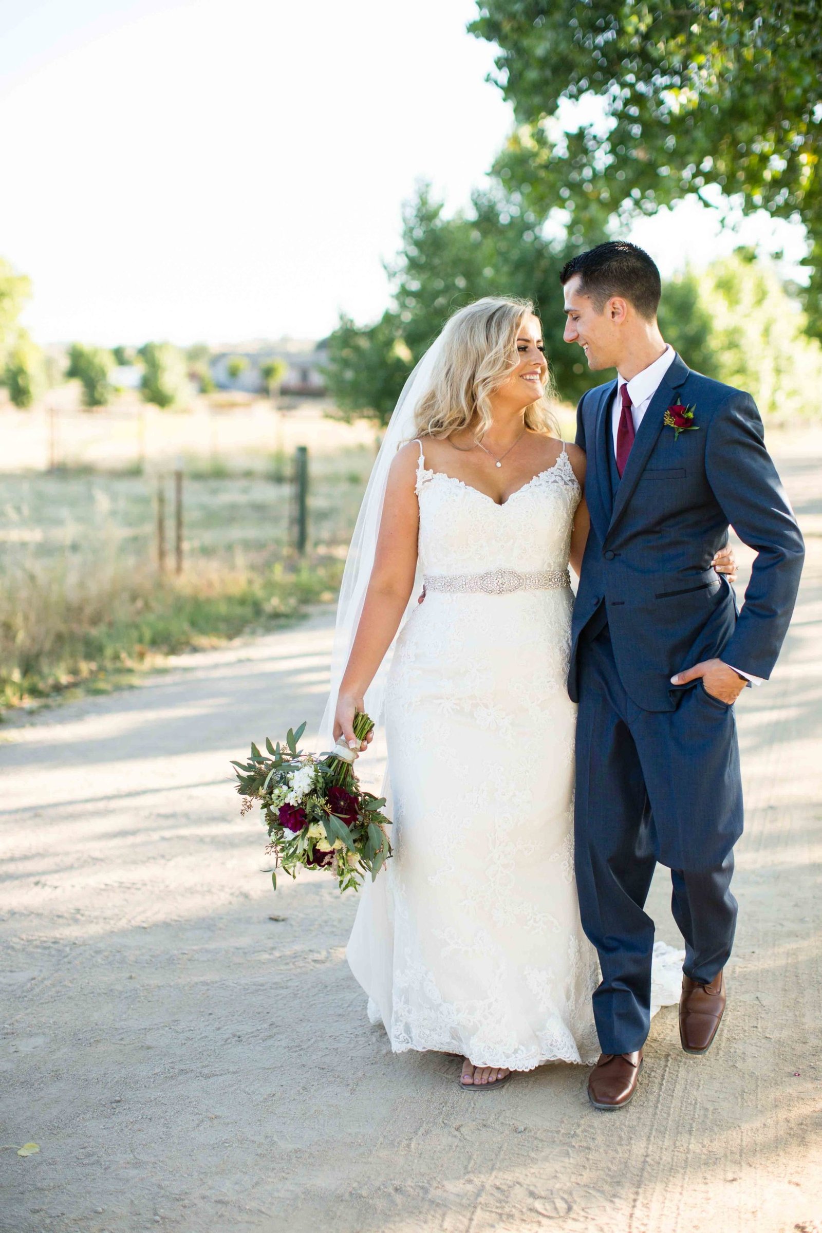 Bride and groom walking down a dirt road at The Loading Chute