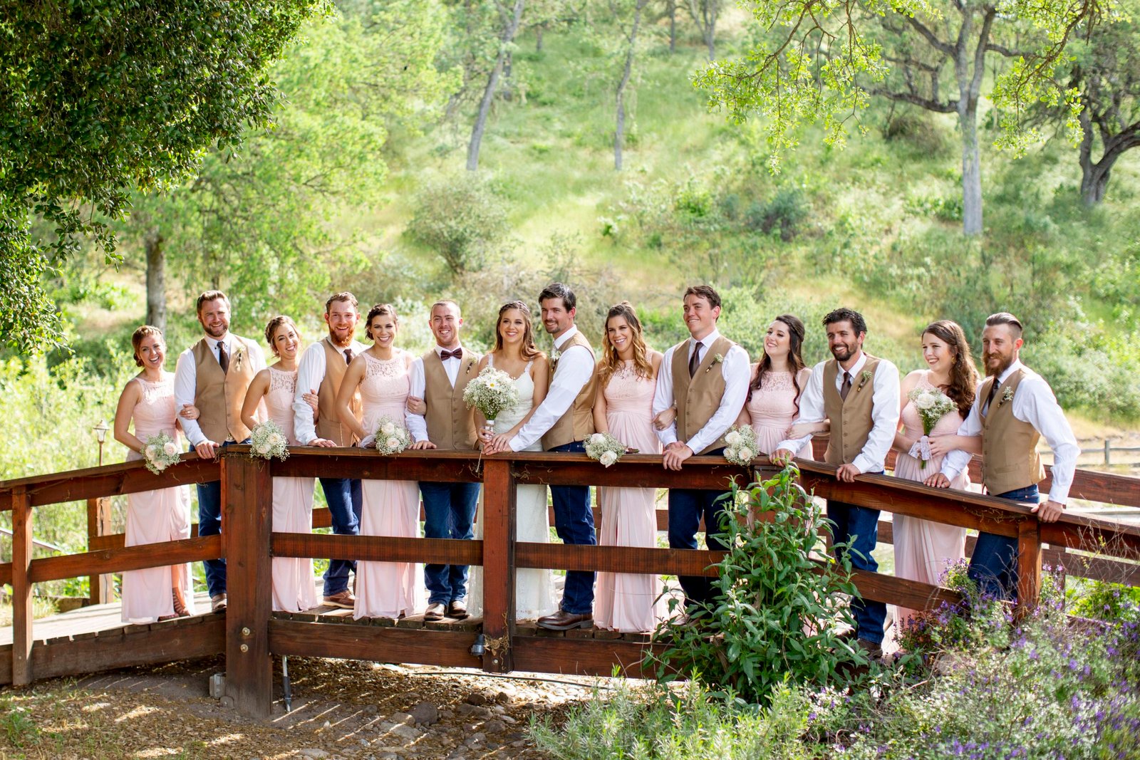 Full wedding party on a wood bridge