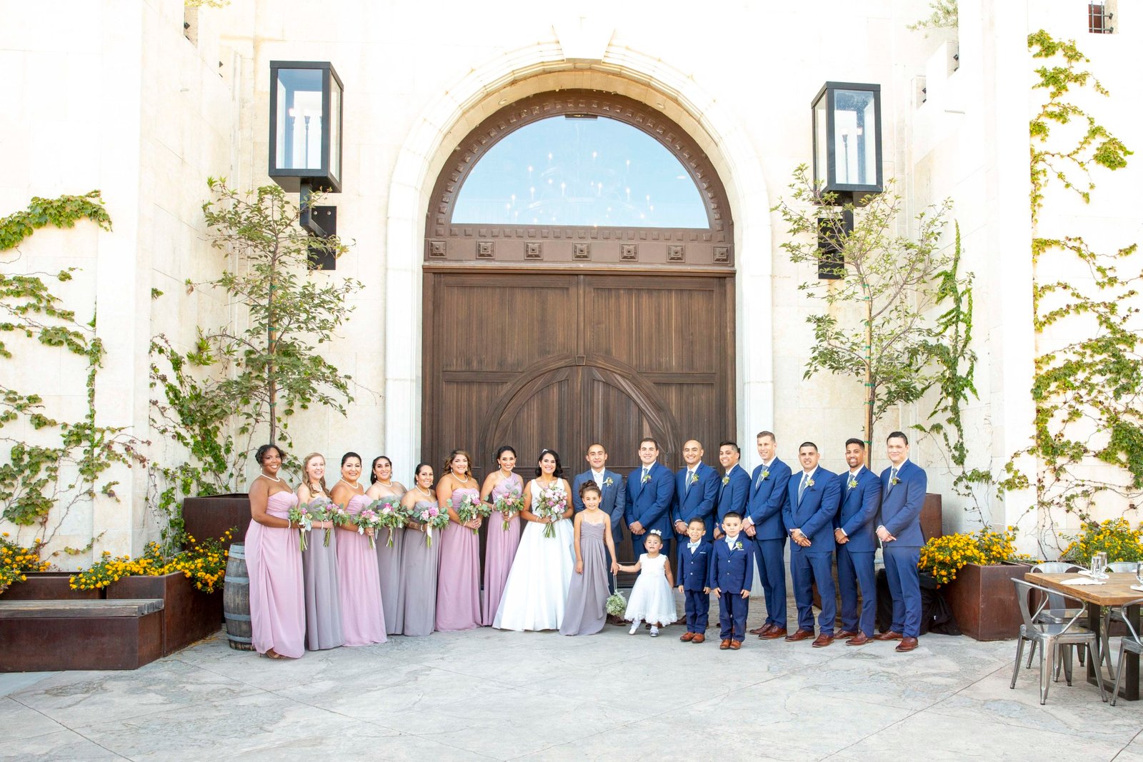 Bride and groom with the full wedding party in front of the main double doors at Tooth and Nail Winery