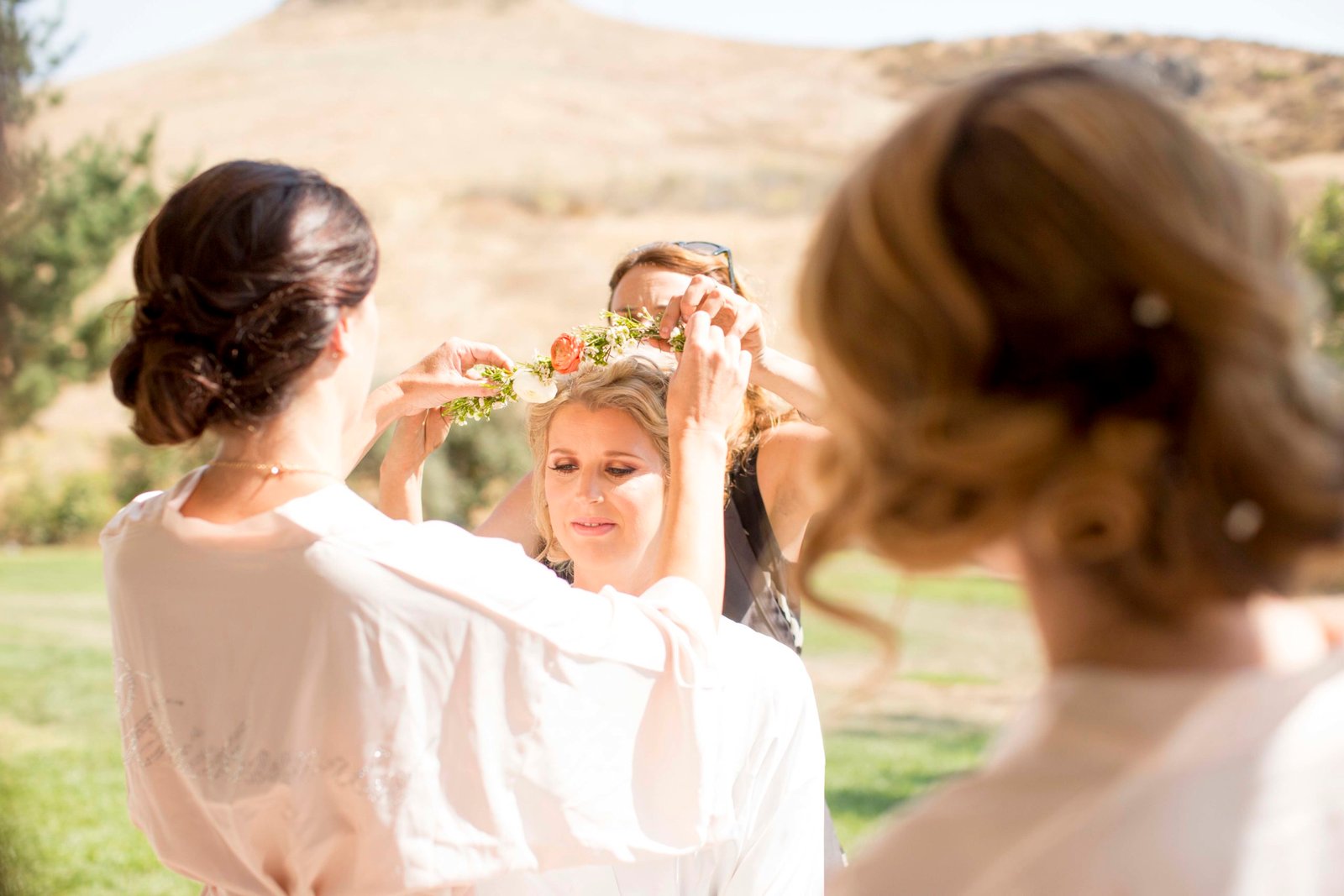 Bridesmaids add a flower crown to the bride at Higuera Ranch