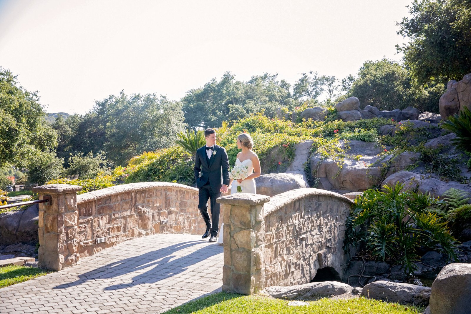 bride and groom walking across a stone bridge
