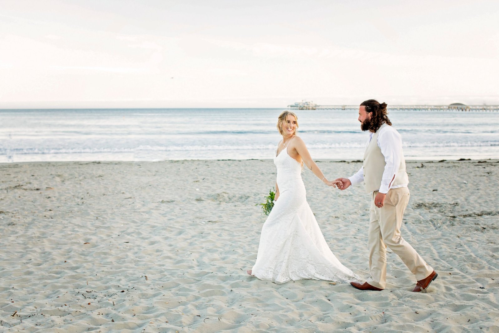 bride and groom walking along the beach holding hands