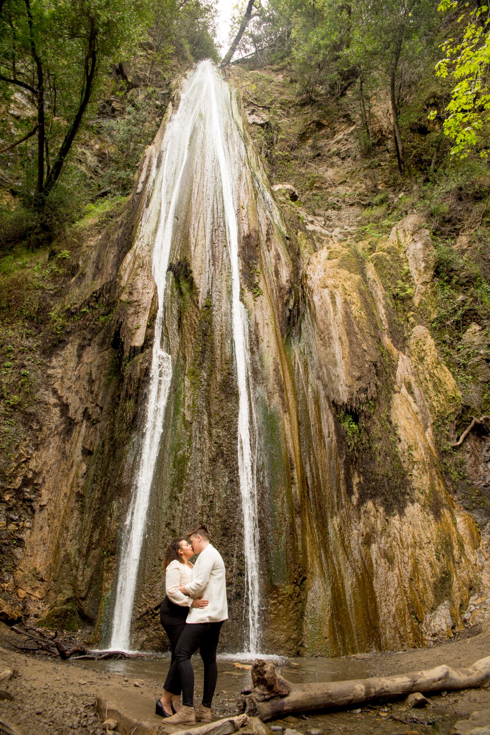 two women embrace during an engagement session at Nojoqui Falls