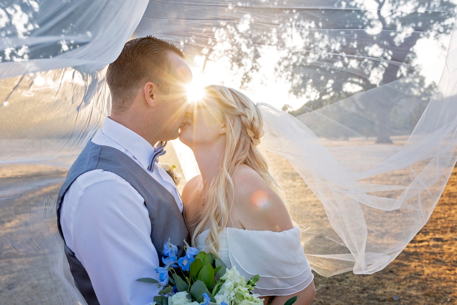 bride and groom kissing under the veil at sunset