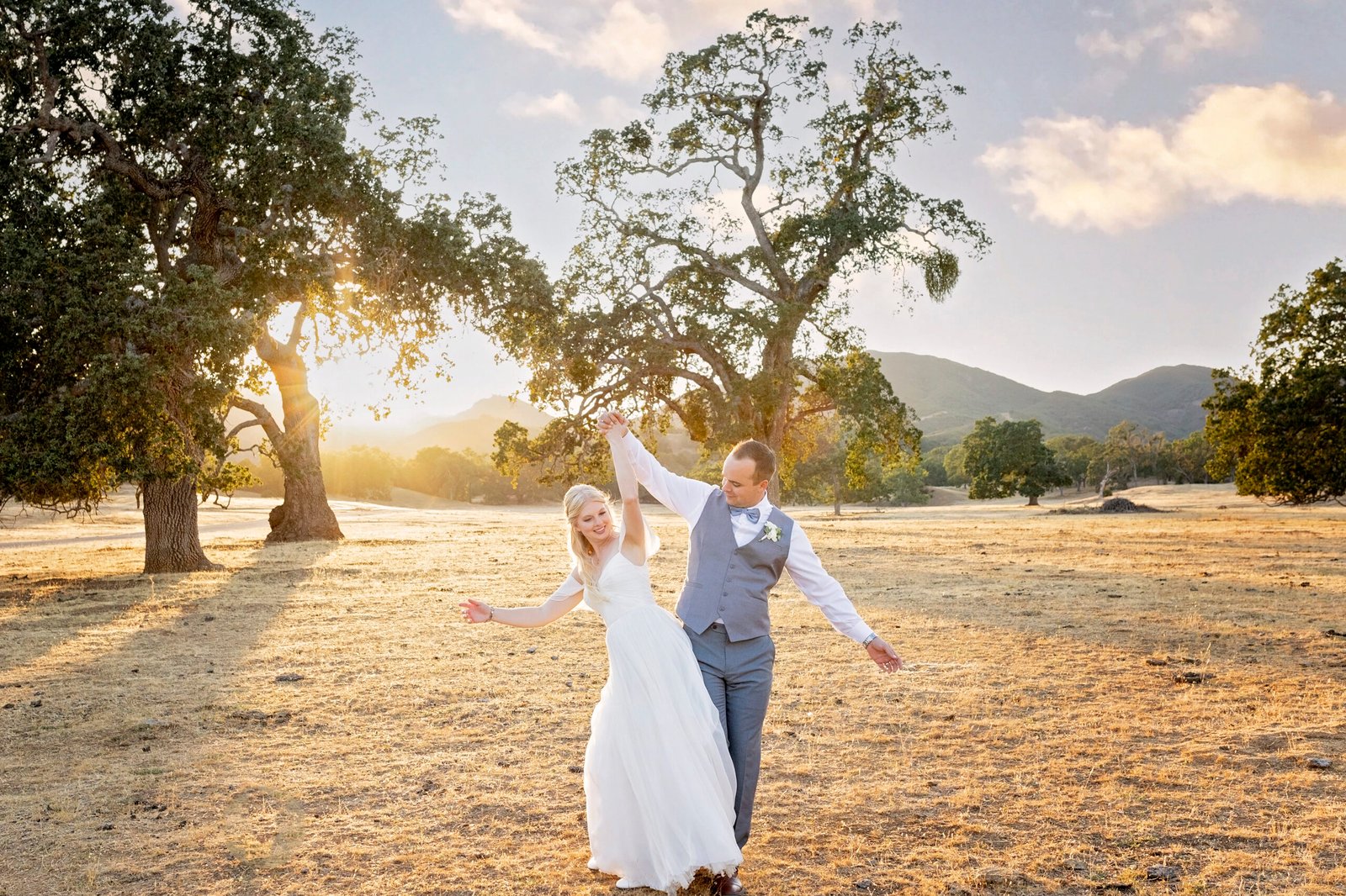 bride and groom bump hips while walking in an open field