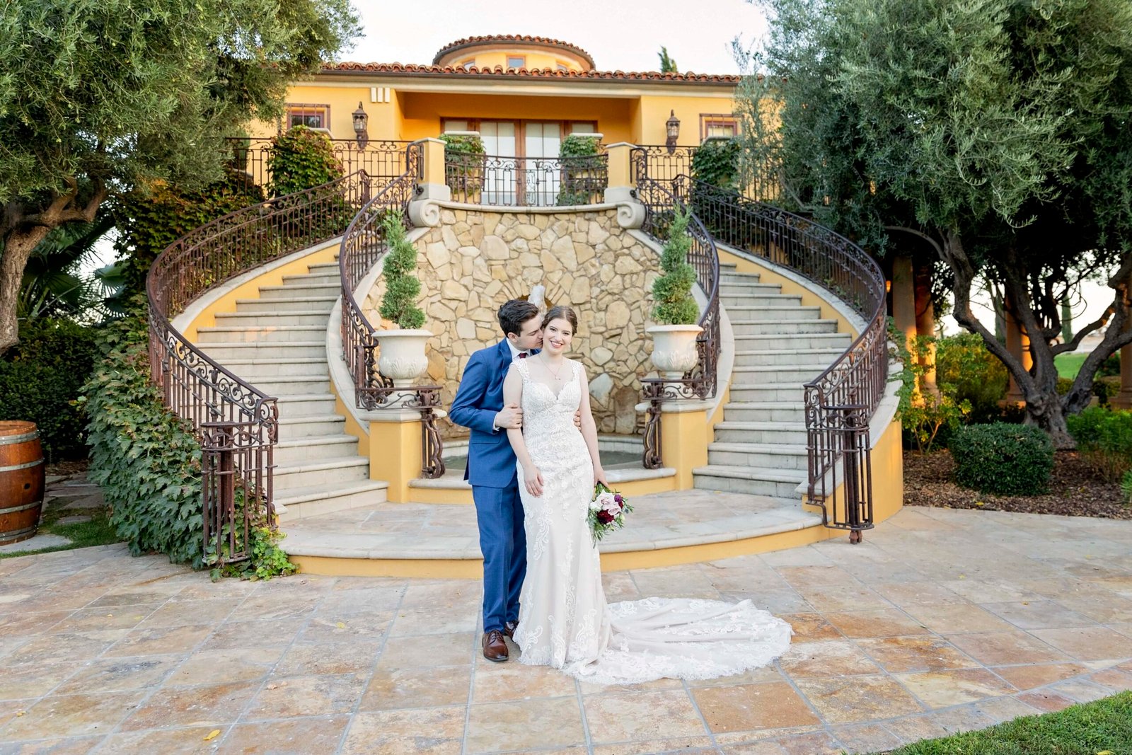 groom kisses the bride in front of a double staircase at CaliPaso Winery