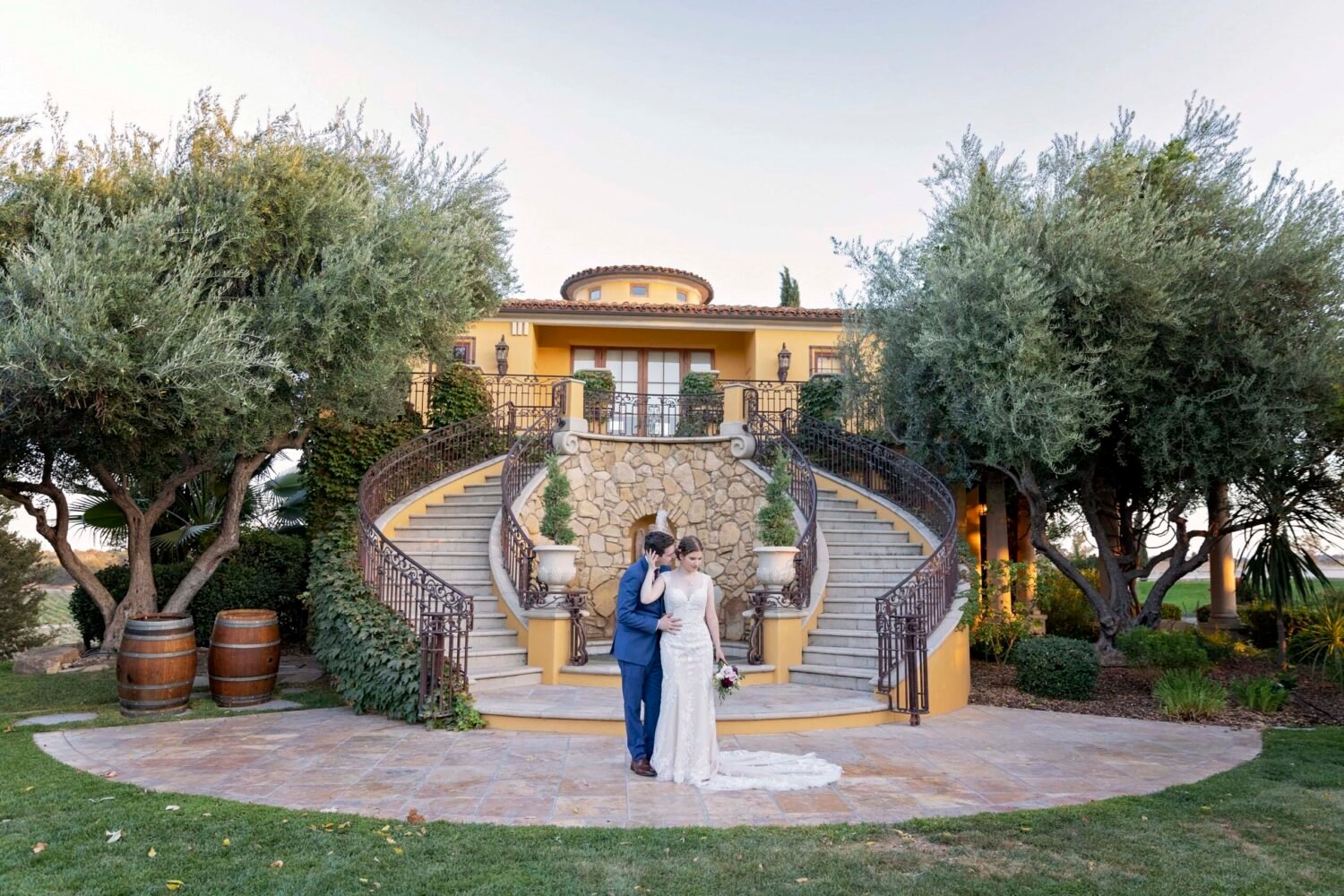 bride and groom pose in front of a double staircase during sunset photos