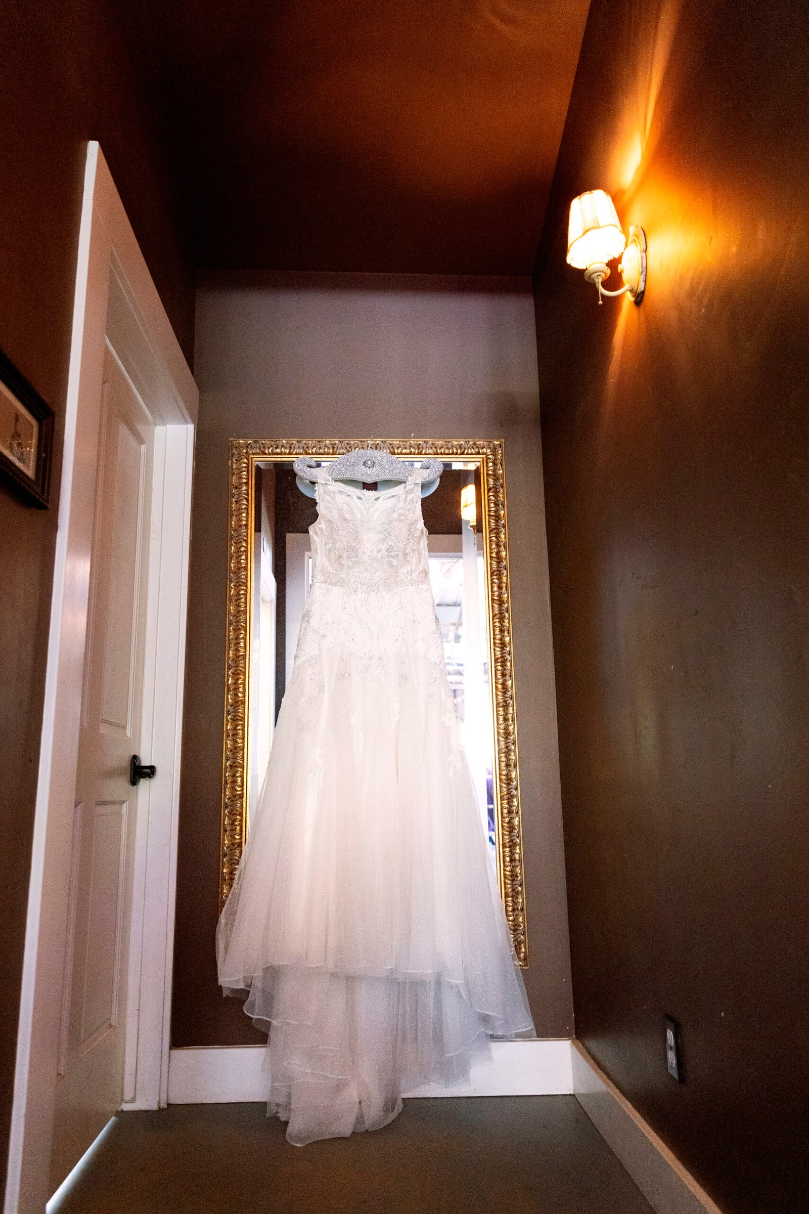 wedding dress hanging from a mirror in a hallway