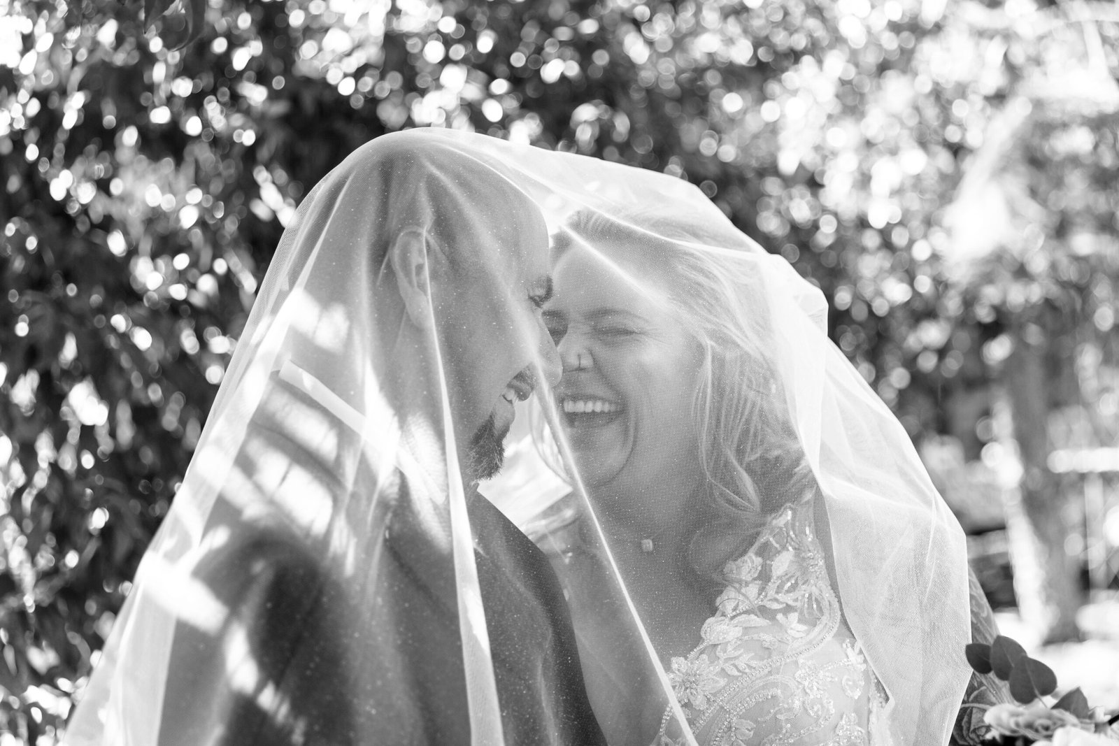 bride and groom laughing under the bride's veil