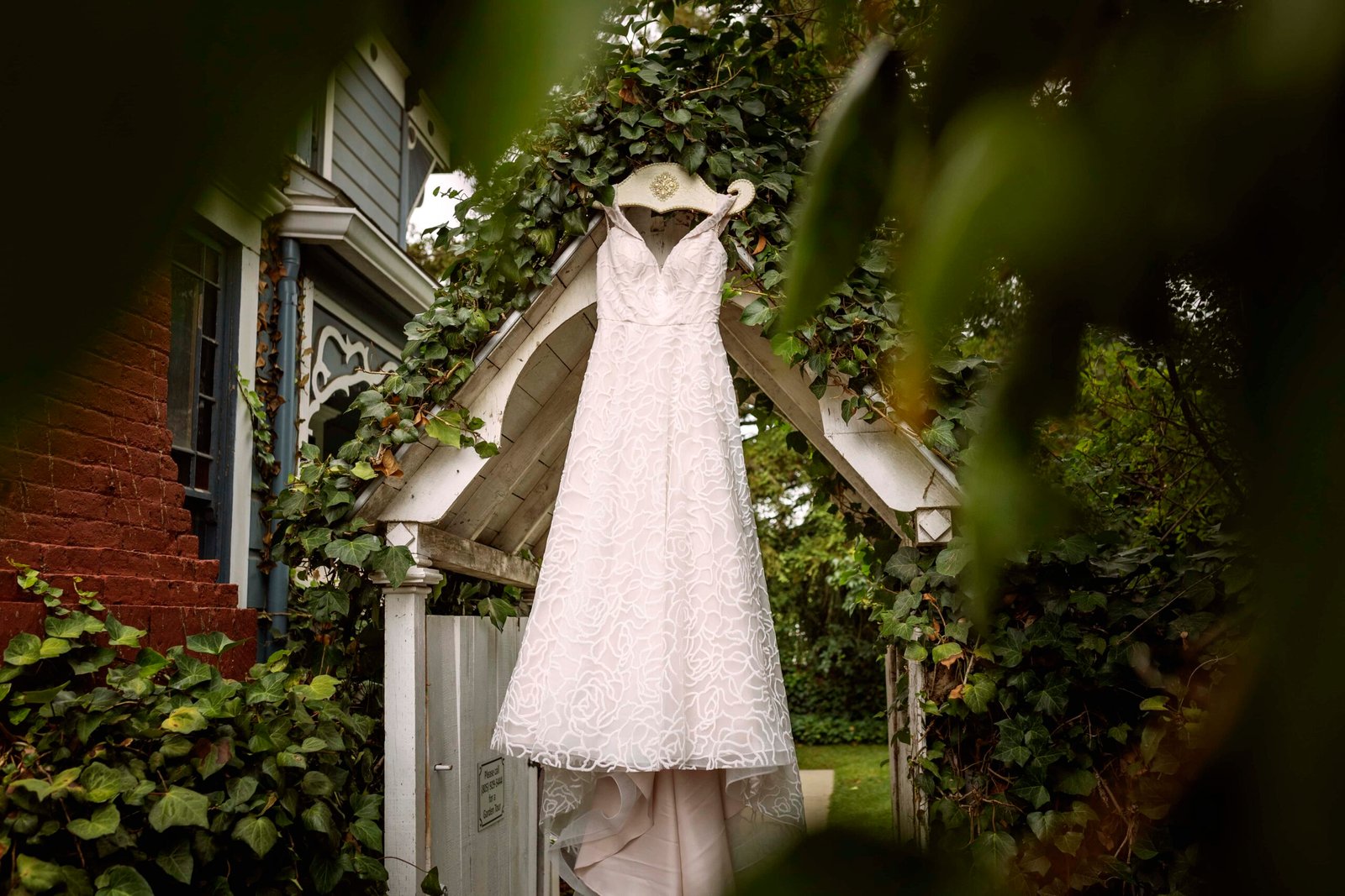 wedding dress hanging from an arbor in a garden