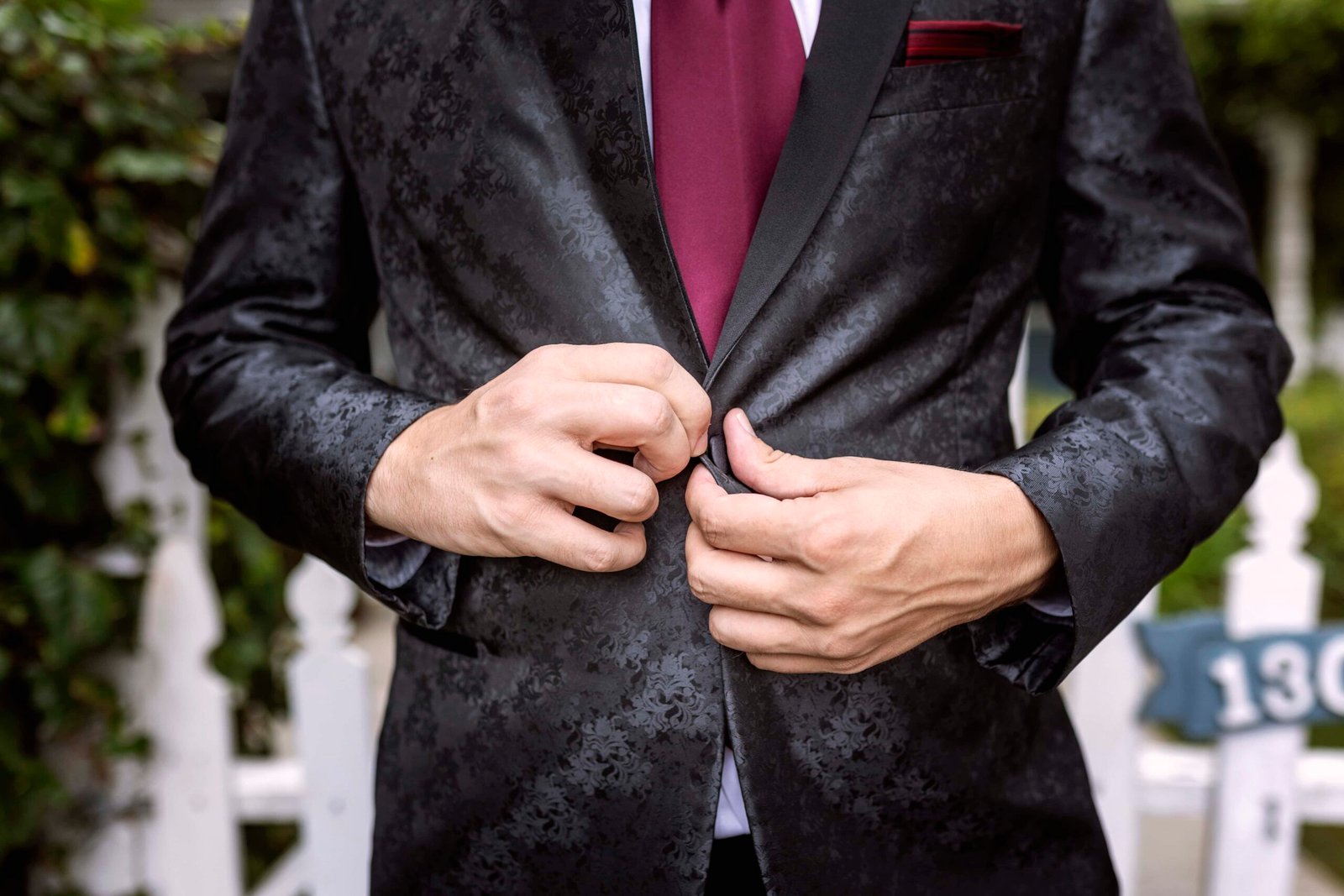 close up of groom buttoning his jacket