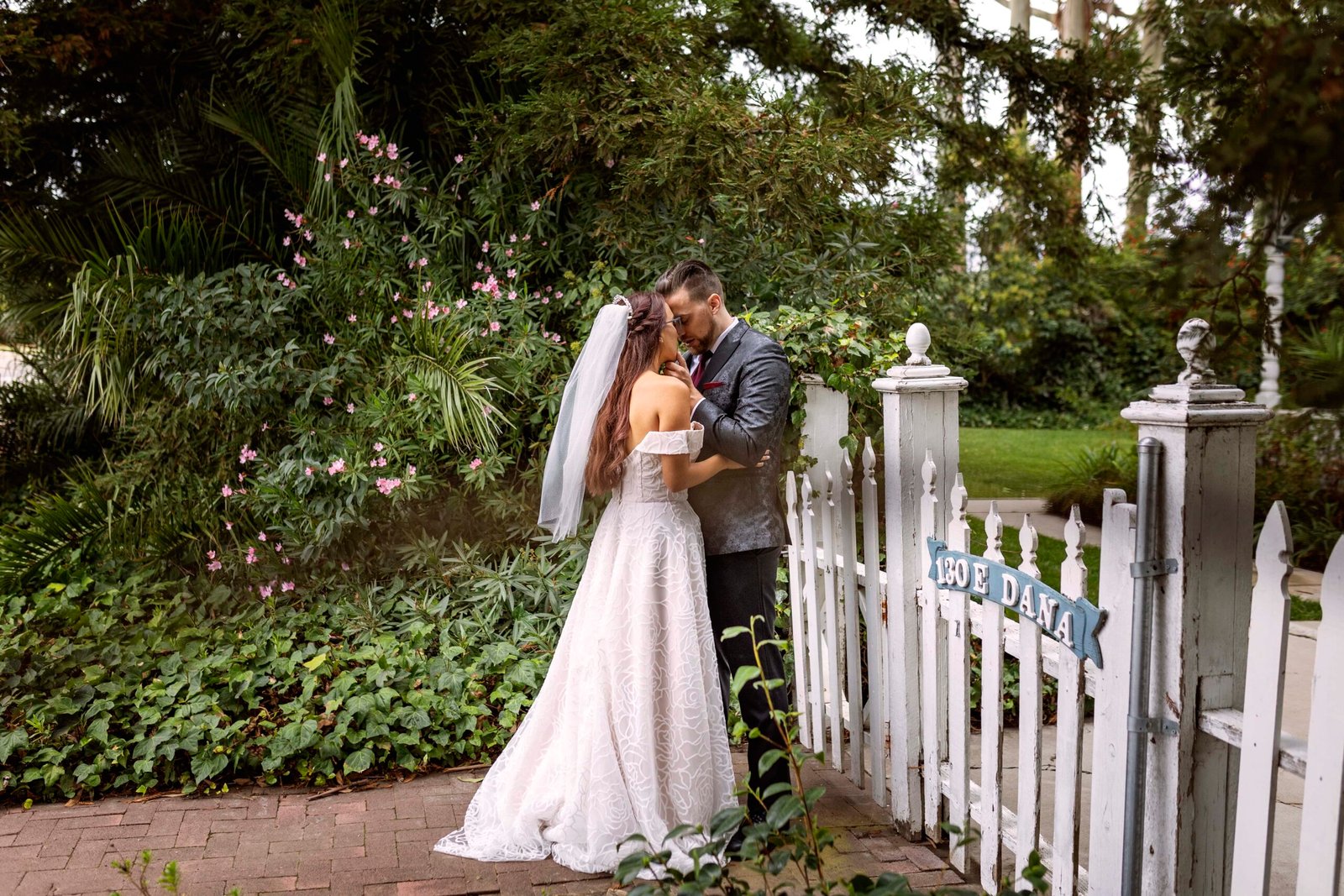 bride and groom in front of a white picket fence