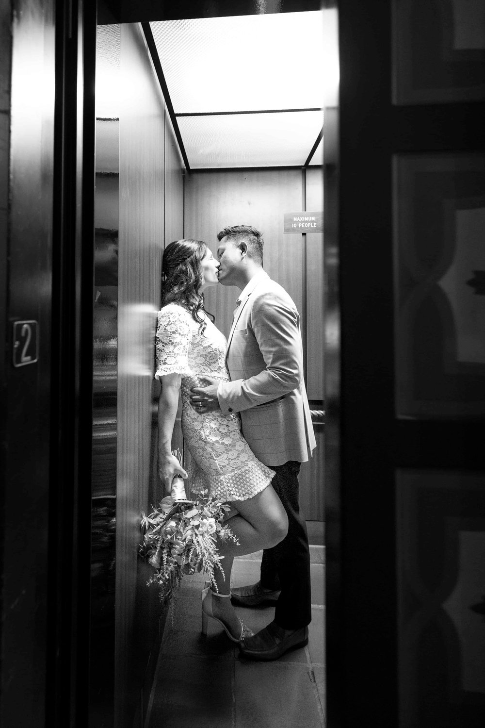 Bride and groom kissing in an elevator as the doors close
