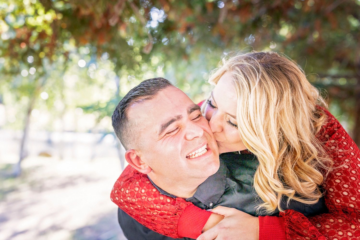 woman kissing her fiance on the cheek while he smiles back at her