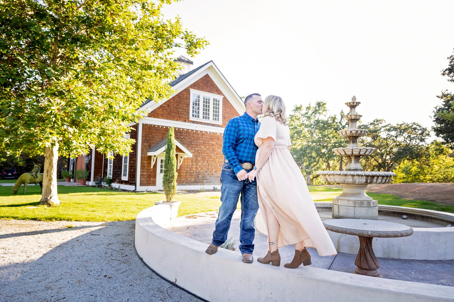 couple kissing at the fountain in front of the barn at Spanish Oaks Ranch