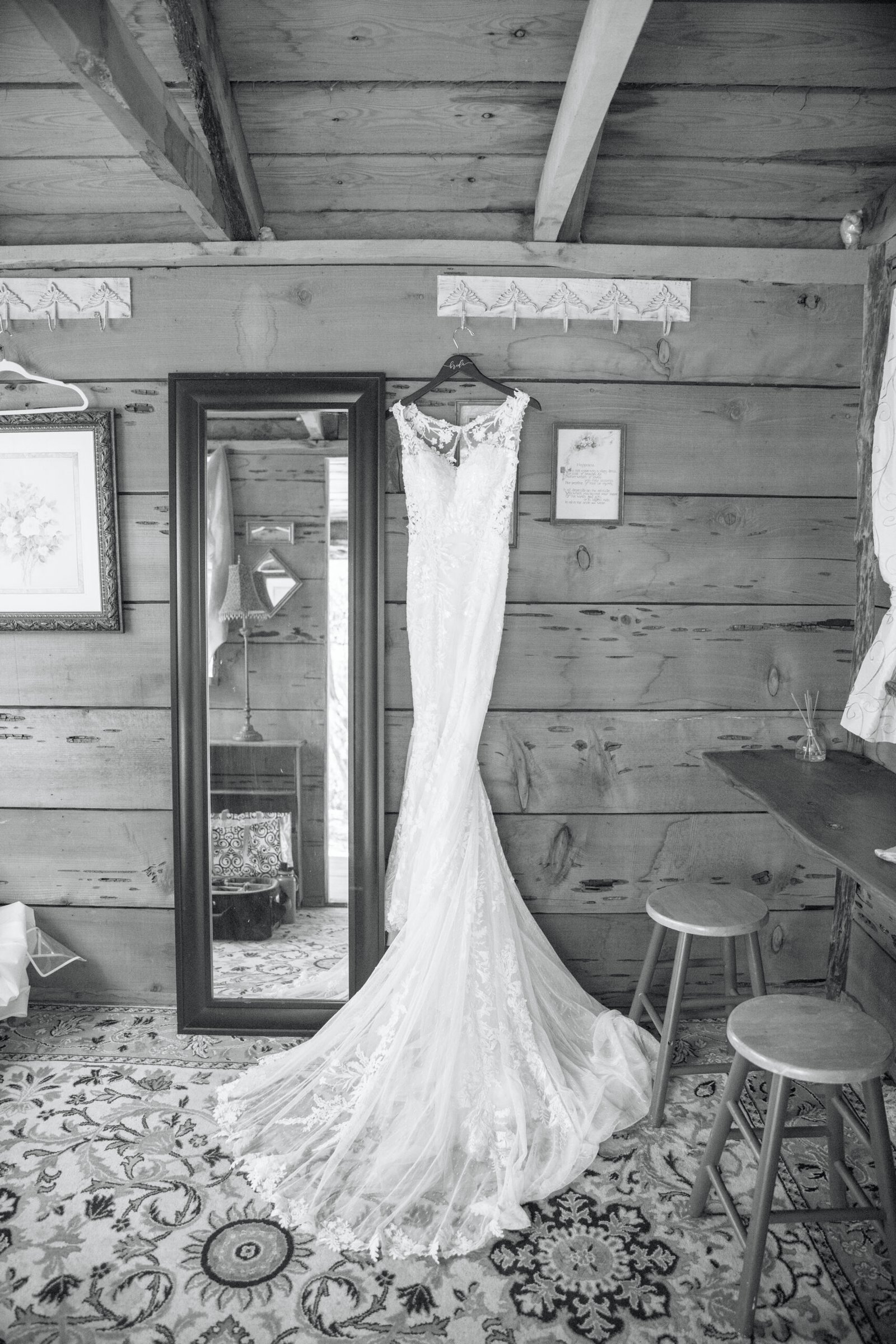 black and white photo of a wedding dress hanging on the wall in a wood cabin