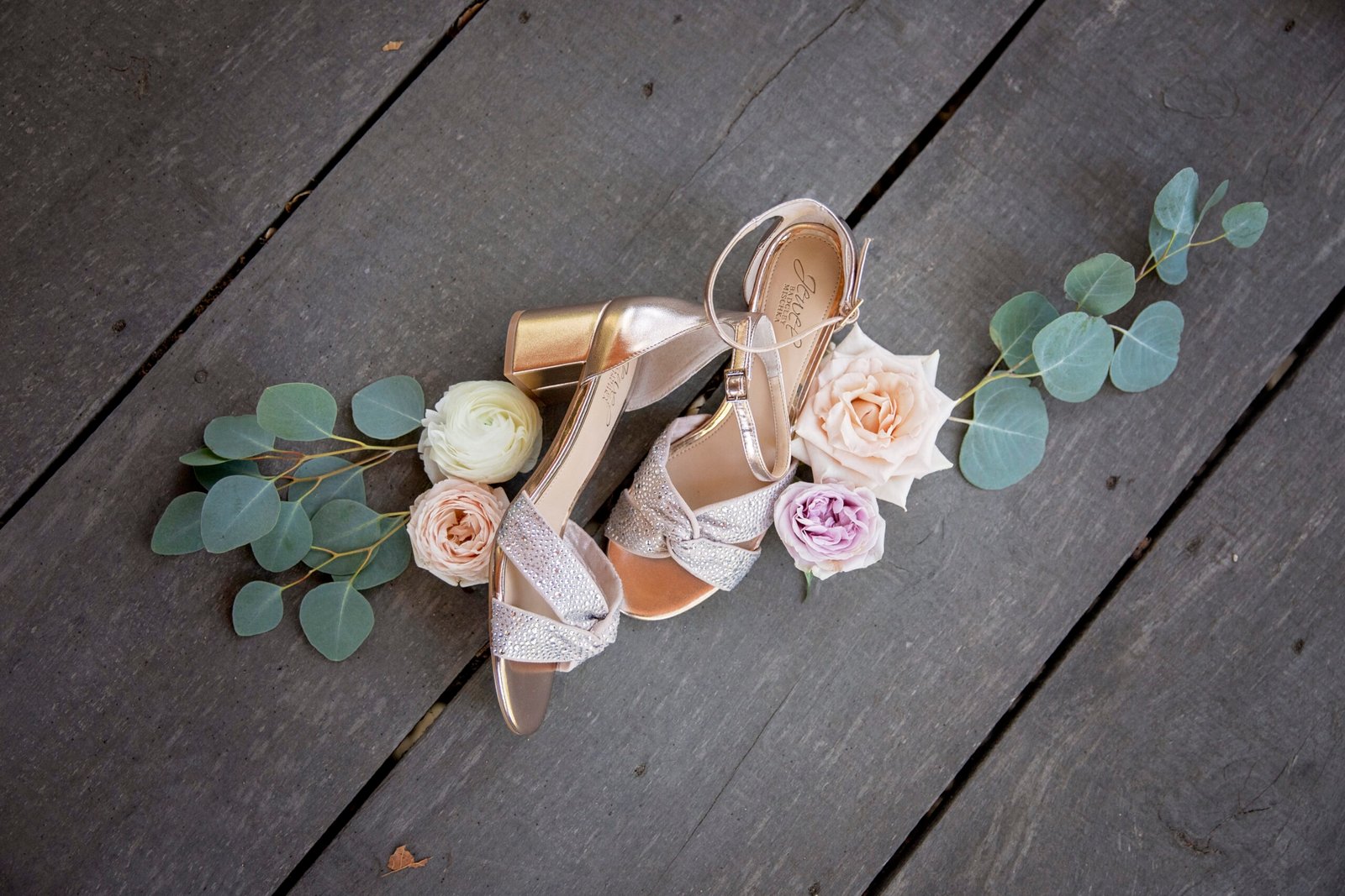 brides shoes with roses and eucalyptus around them