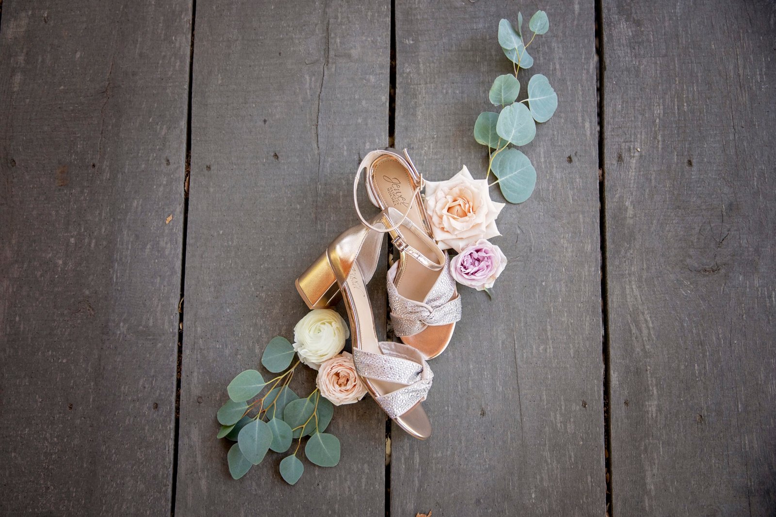 brides shoes with roses and eucalyptus around them