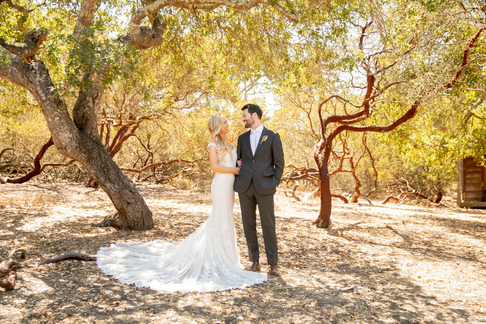 bride and groom looking at each other under oak and manzanita trees