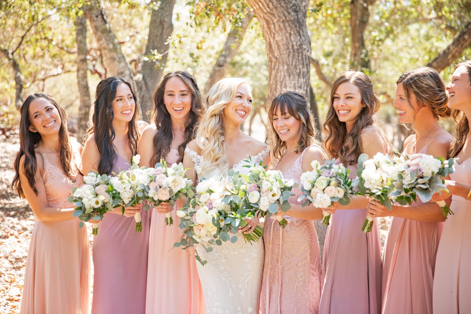 bride smiling at her bridesmaids while they all hold bouquets