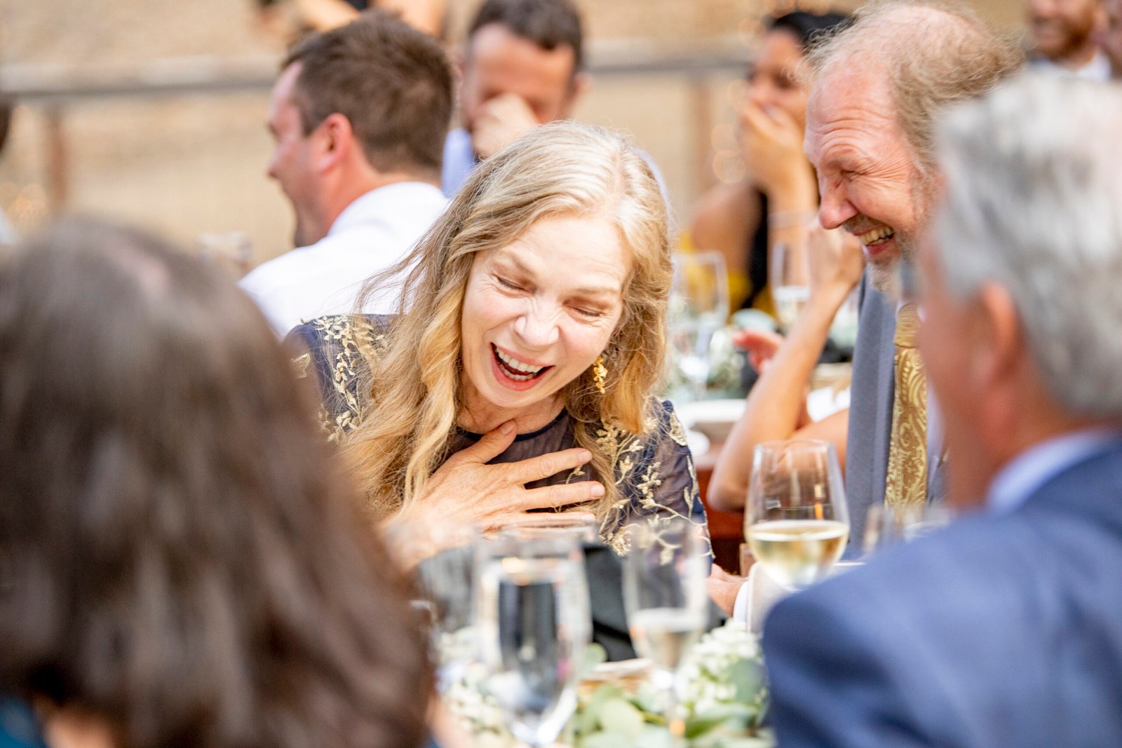 mother of the bride laughing during speeches at a wedding reception