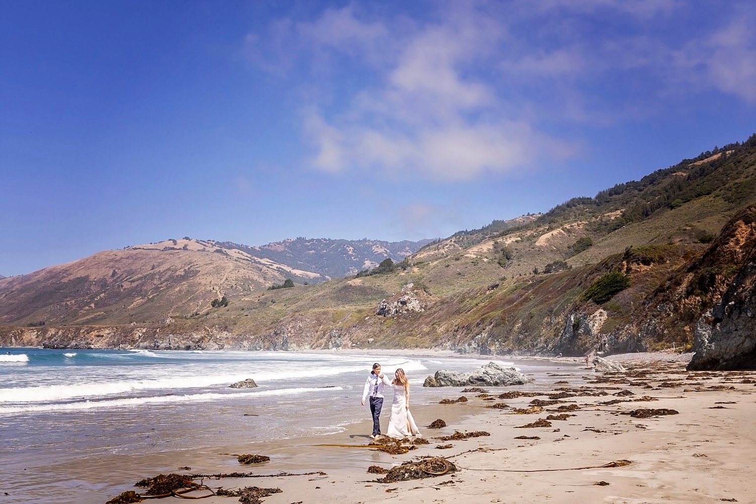 couple walking together on the beach holding hands during and engagement session