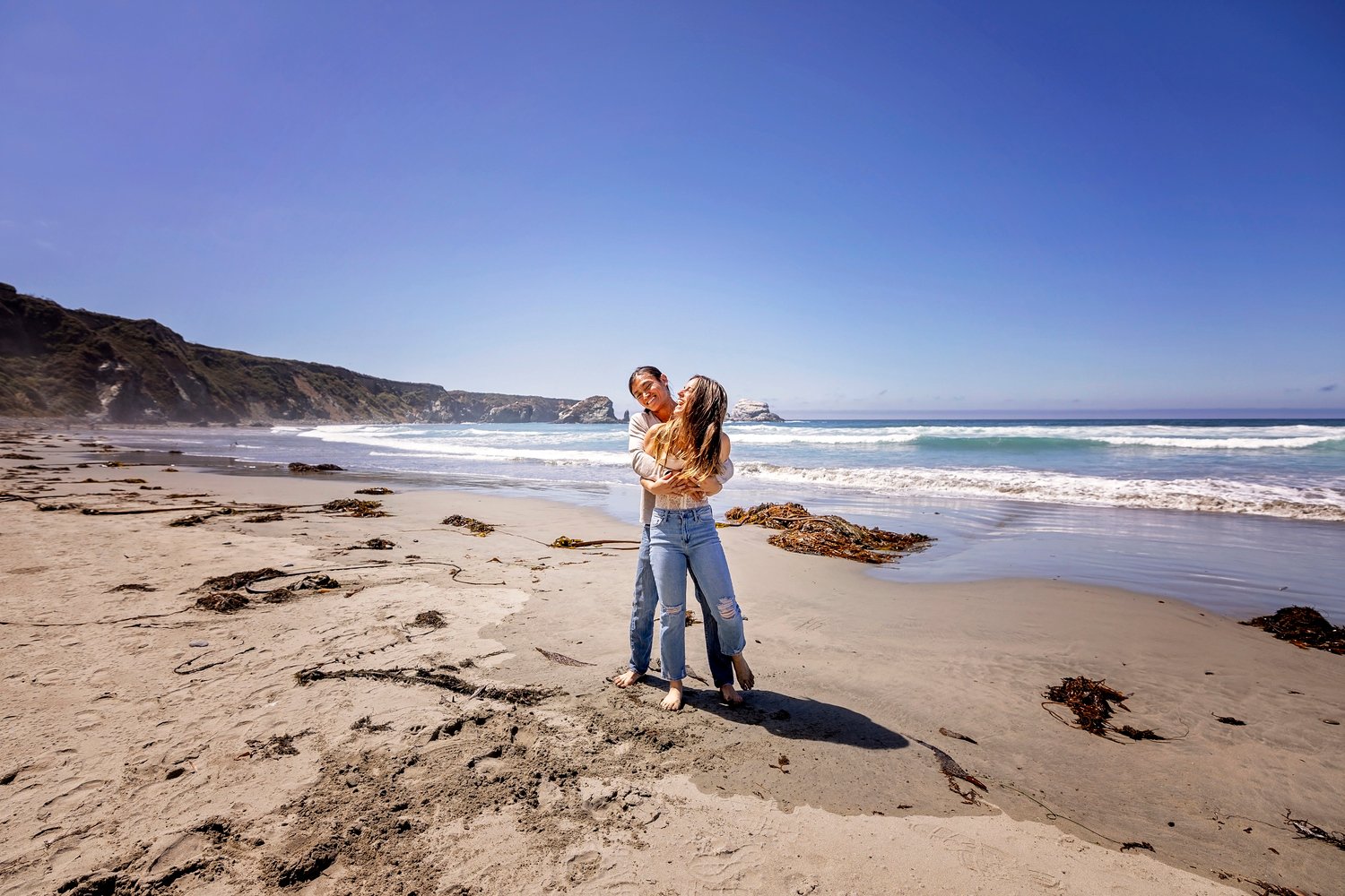 couple playing with each other on the beach during an engagement session