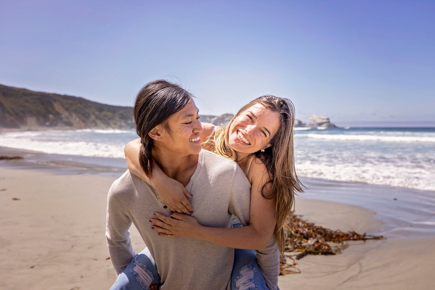 couple smiling at the camera during an engagement session on the beach