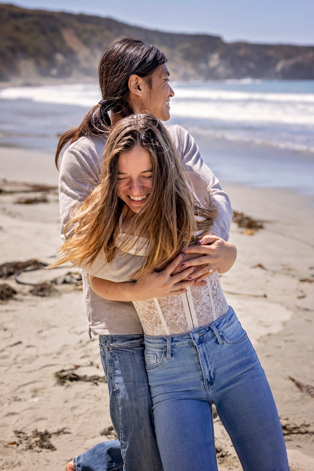 couple playing with each other on the beach during an engagement session