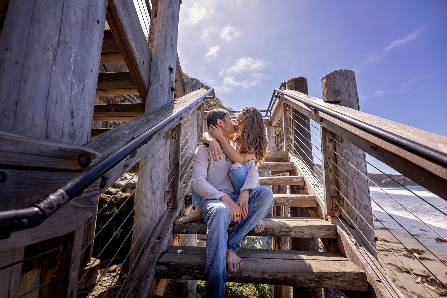 Couple kissing on wooden stairs at the beach