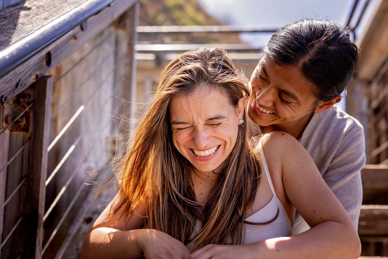 girl laughing with her fiance while sitting on the stairs at Sand Dollar Beach