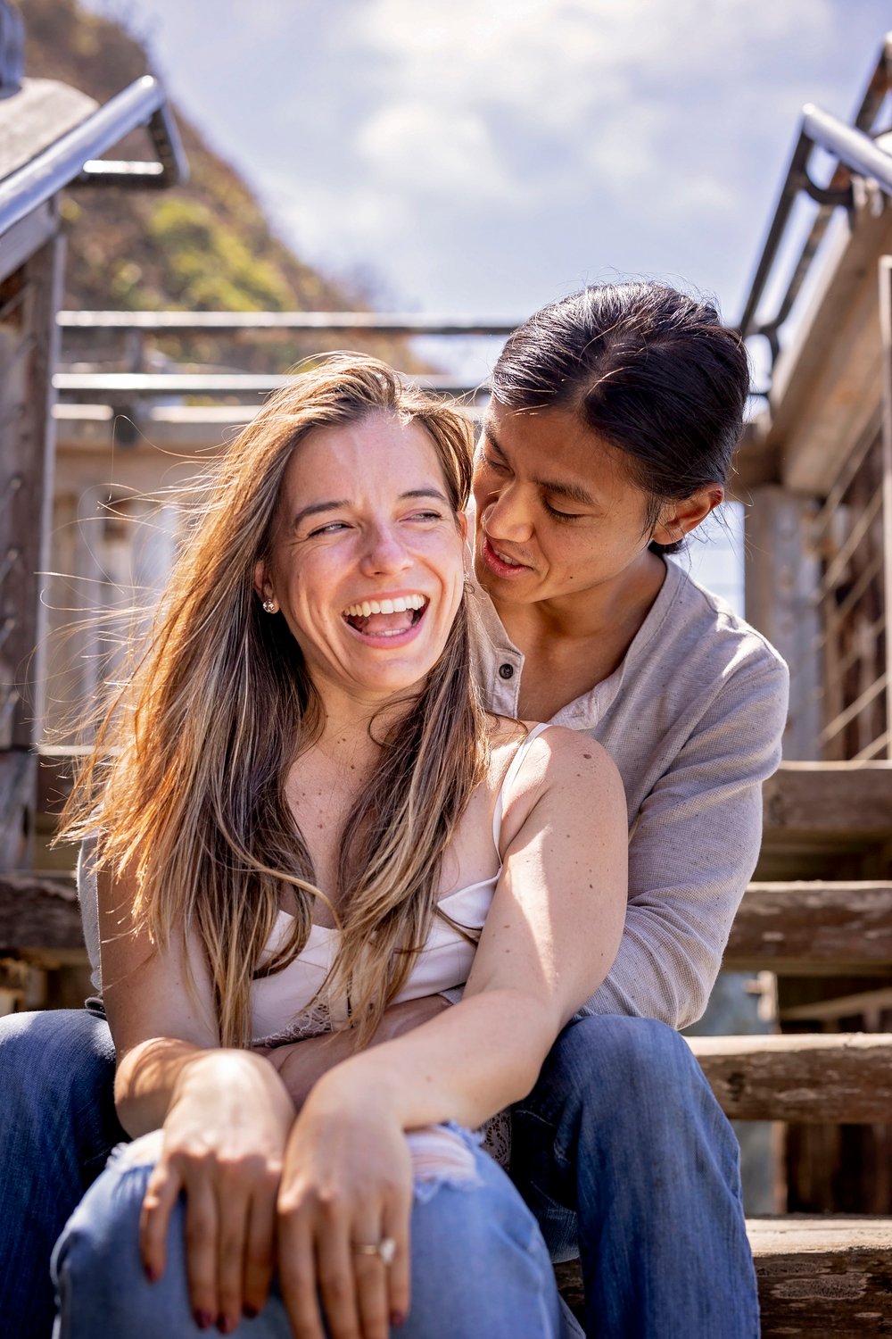 girl laughing with her fiance while sitting on the stairs at Sand Dollar Beach