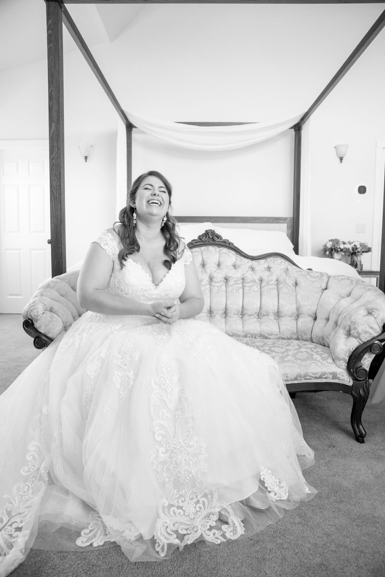 bride laughing while sitting in an antique sofa in her wedding dress