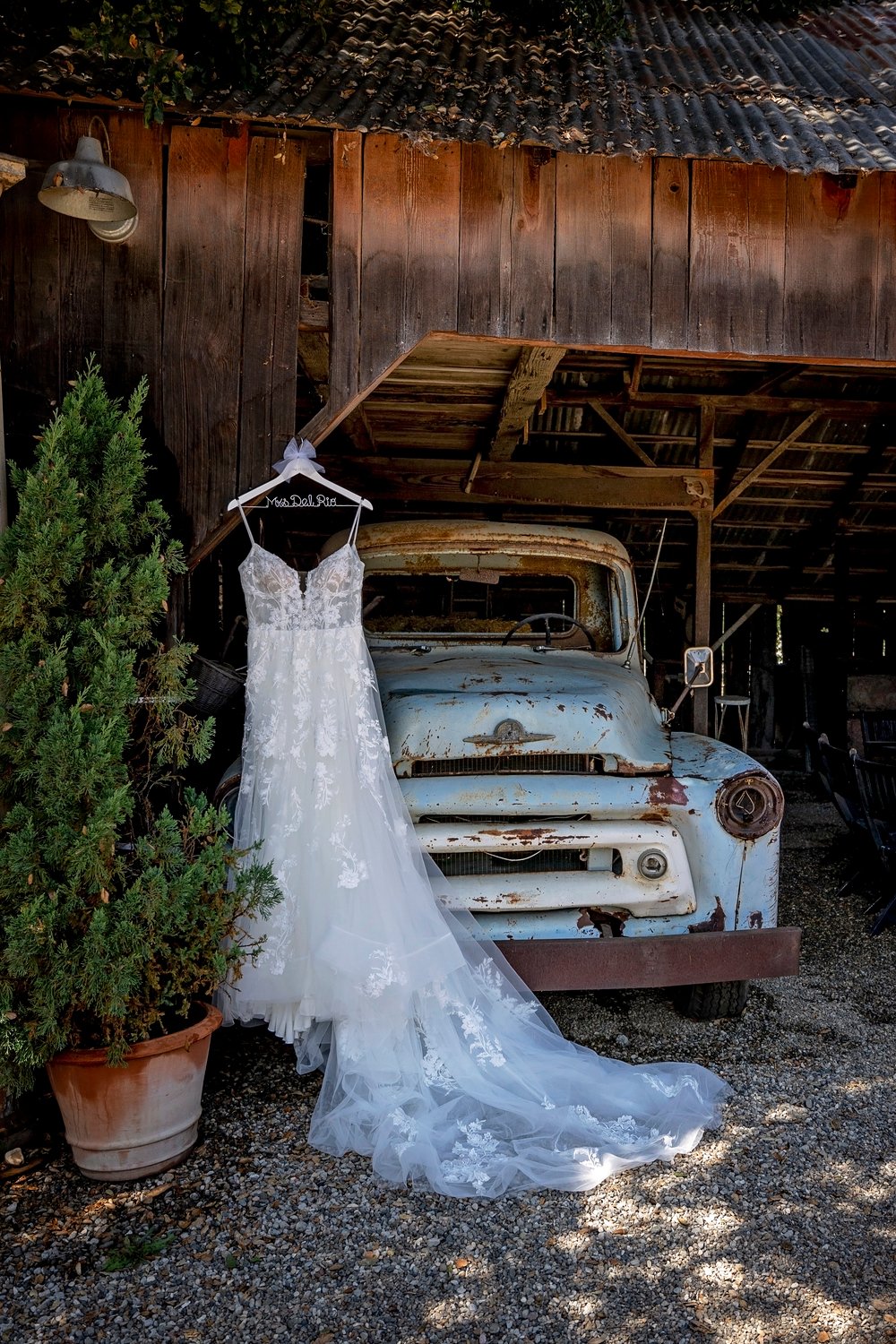 wedding dress hanging at a barn in front of a vintage truck