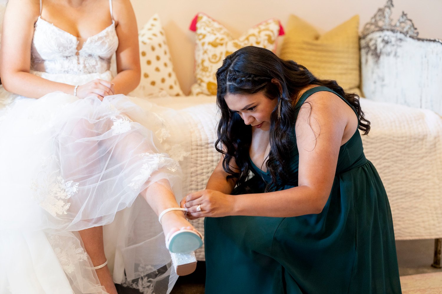 bridesmaid helping the bride put her shoes on