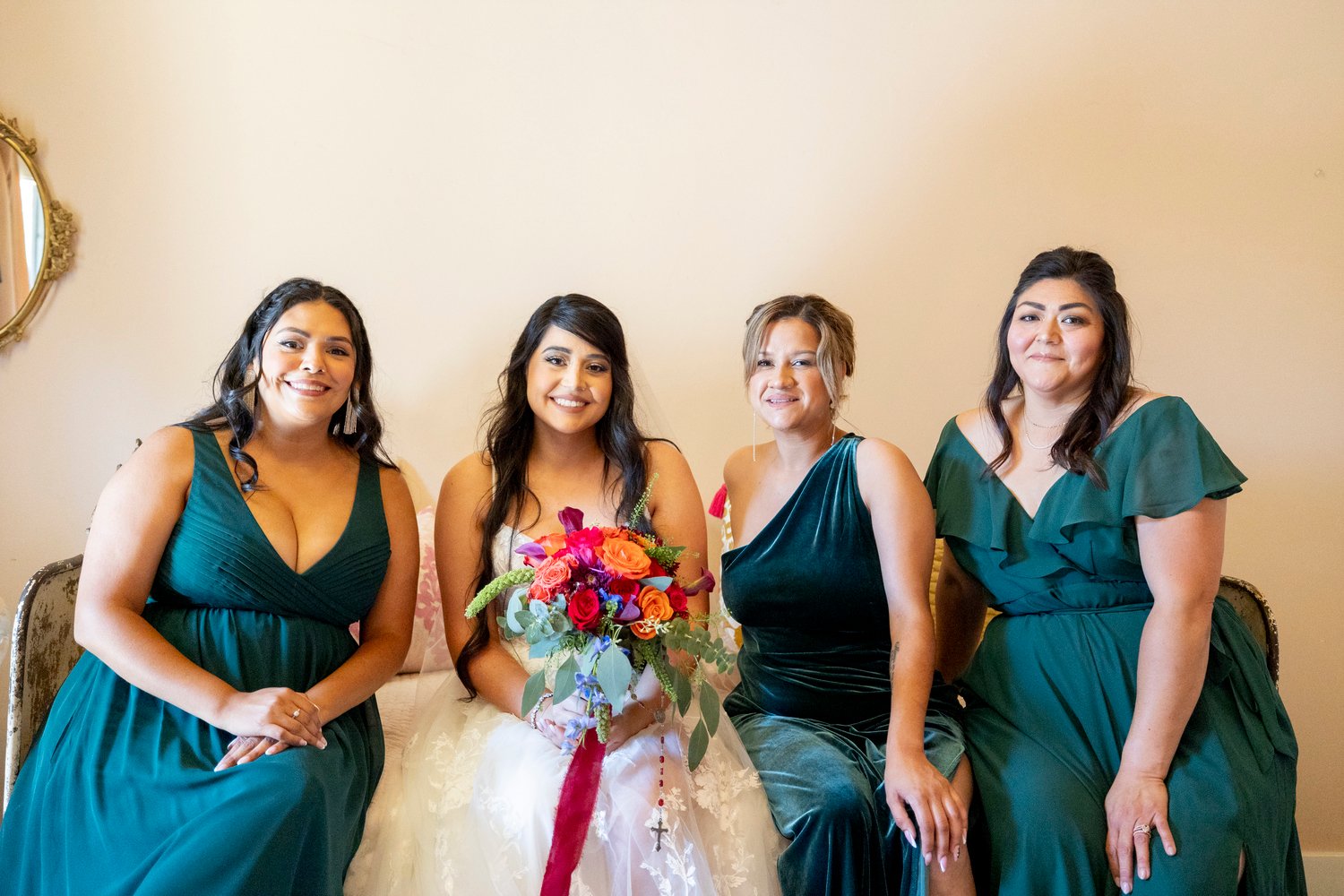 bride and bridesmaids smiling while sitting on a bed