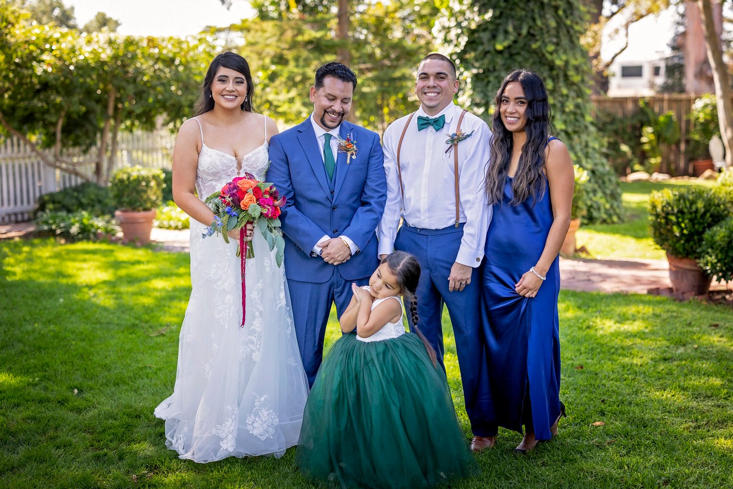 bride and groom posing with family on a grassy lawn